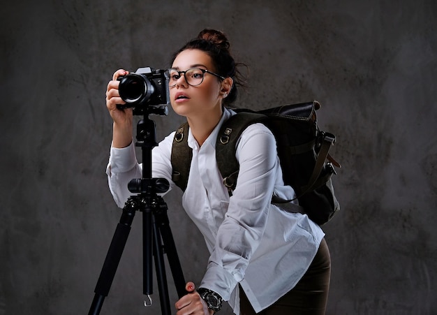 Mujer viajera tomando fotografías con una cámara digital en un trípode.