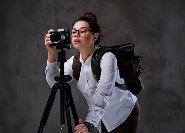 Mujer viajera tomando fotografías con una cámara digital en un trípode.