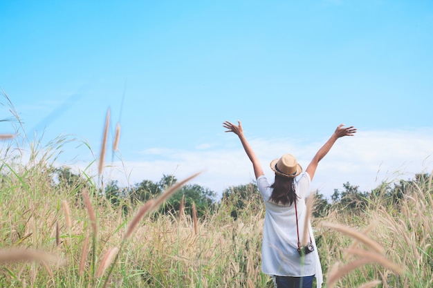 Mujer viajero con cámara empujar las manos y la respiración en el campo de hierbas y el bosque, wanderlust viaje concepto, espacio para texto, atmosperic epic momento