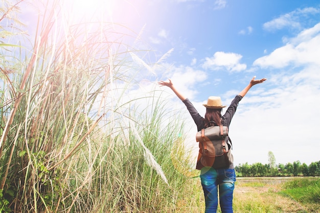 Mujer viajero empujar las manos y la respiración en el campo de hierbas y cielo azul, wanderlust concepto de viaje, el espacio para el texto