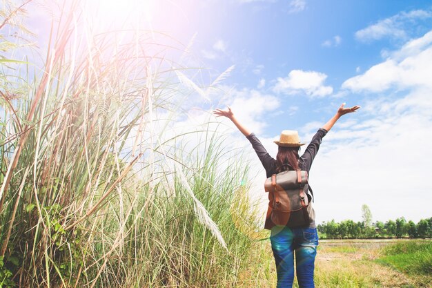 Mujer viajero empujar las manos y la respiración en el campo de hierbas y cielo azul, wanderlust concepto de viaje, el espacio para el texto