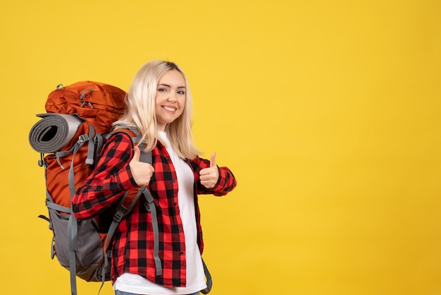 Mujer de viajero rubia vista frontal con su mochila dando pulgar hacia arriba