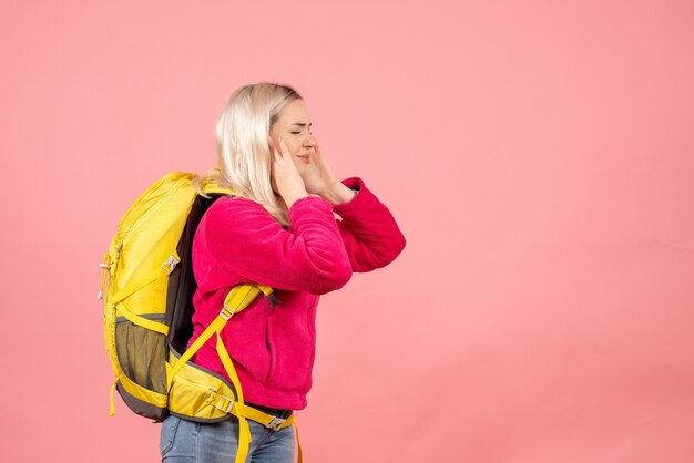 Mujer de viajero de vista frontal con mochila cerrando las orejas con las manos