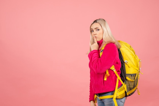 Mujer de viajero de vista frontal con mochila haciendo señal de silencio