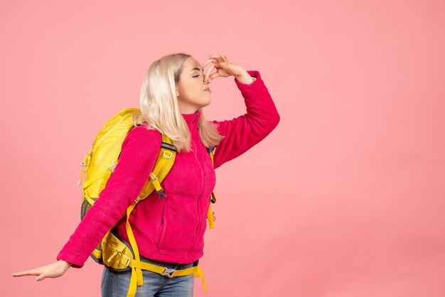 Mujer de viajero de vista frontal con mochila sosteniendo la nariz