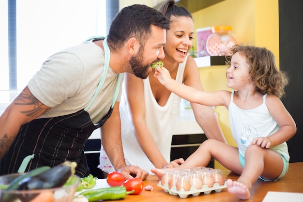 Mujer viendo hija alimentando pimiento a su padre