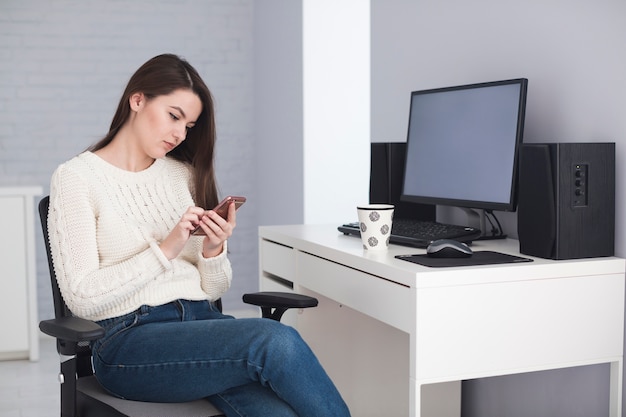 Foto gratuita mujer viendo el teléfono inteligente en la oficina en casa