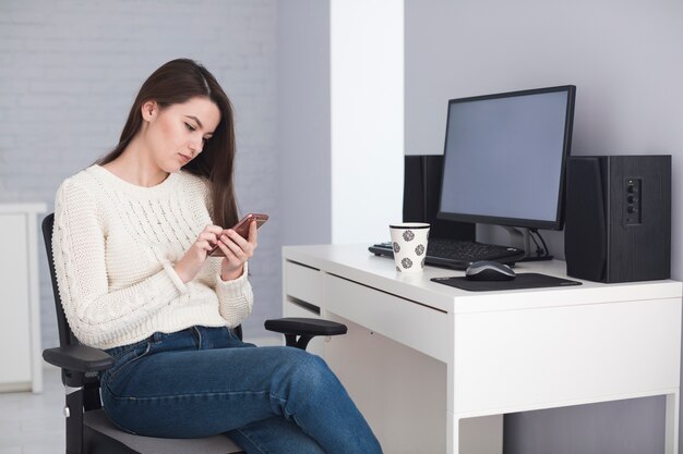 Mujer viendo el teléfono inteligente en la oficina en casa