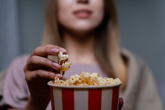 Mujer viendo la televisión y comiendo palomitas de maíz de cerca