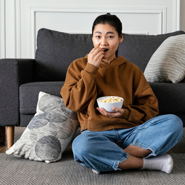 Mujer viendo la televisión y comiendo palomitas de maíz