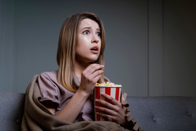 Mujer viendo la televisión y comiendo palomitas de maíz