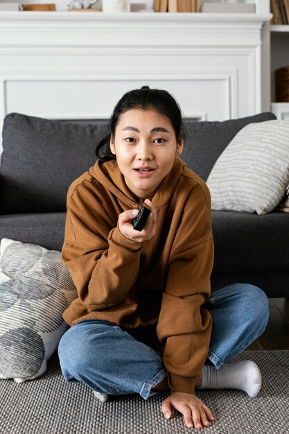 Mujer viendo la televisión y sosteniendo el control remoto