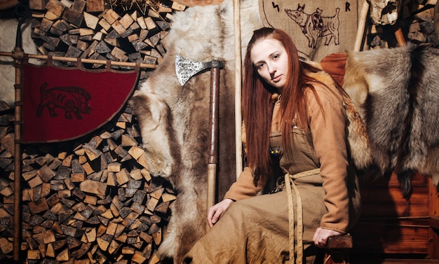 Mujer vikinga posando contra el antiguo interior de los vikingos.