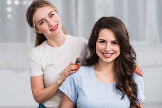 Mujer visagiste con cliente sonriendo a cámara