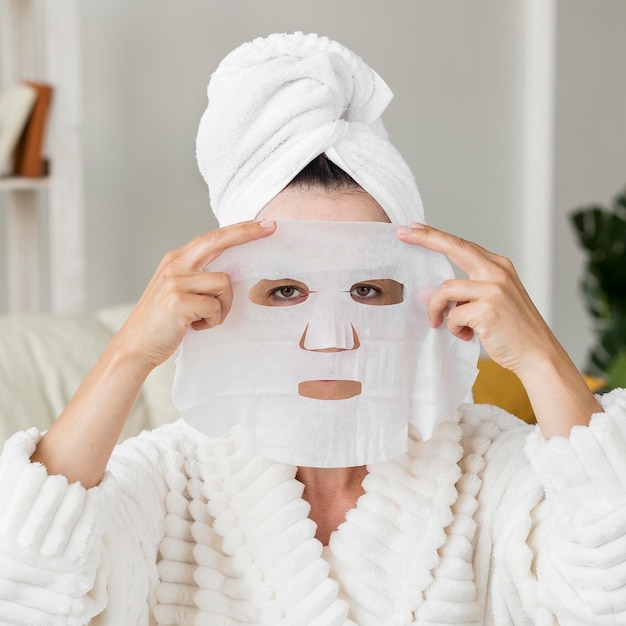Mujer de vista frontal aplicando mascarilla facial
