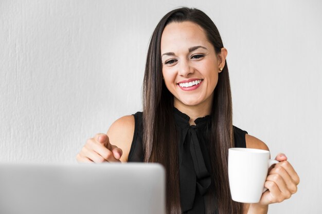 Mujer vista frontal disfrutando de su taza de café en la oficina