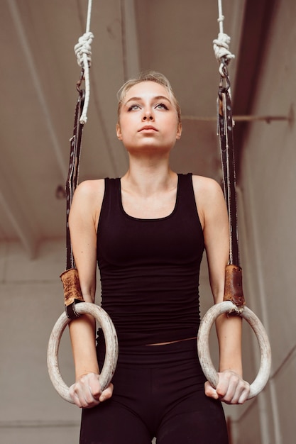 Foto gratuita mujer de vista frontal entrenando en anillos de gimnasia