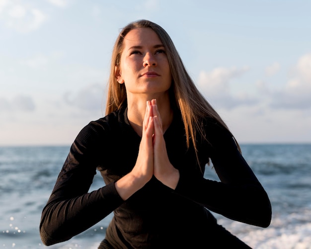 Mujer de vista frontal meditando en la playa