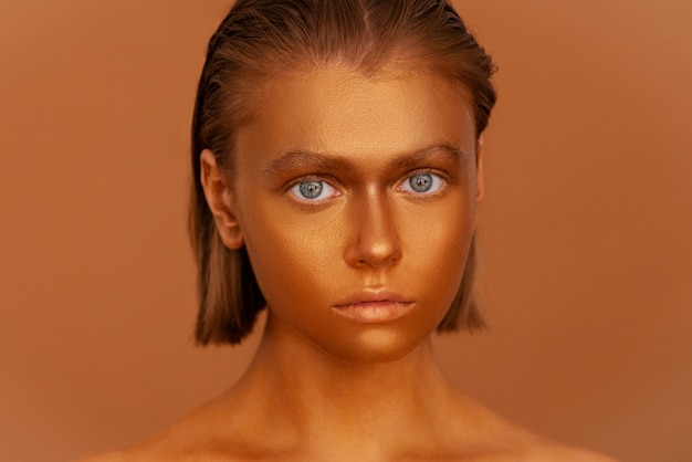 Foto gratuita mujer de vista frontal posando con pintura corporal dorada