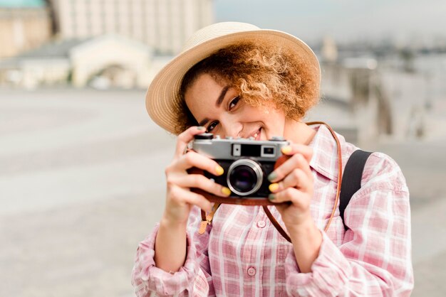 Mujer de vista frontal tomando una foto con una cámara mientras viaja