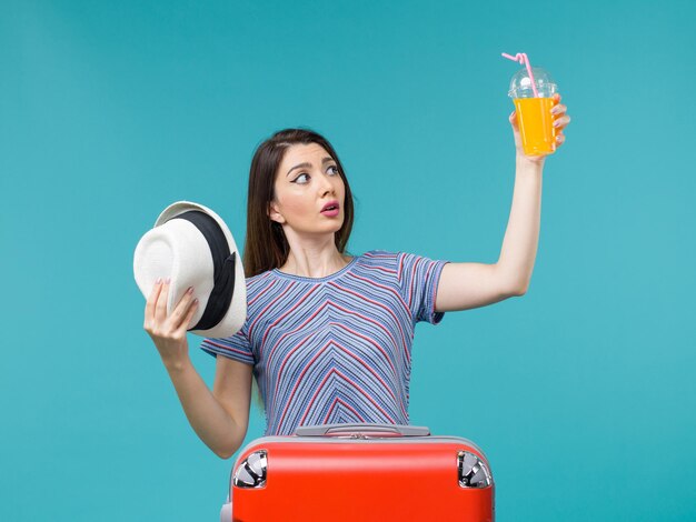 Mujer de vista frontal en vacaciones con jugo y sombrero sobre fondo azul viaje de vacaciones viaje por mar