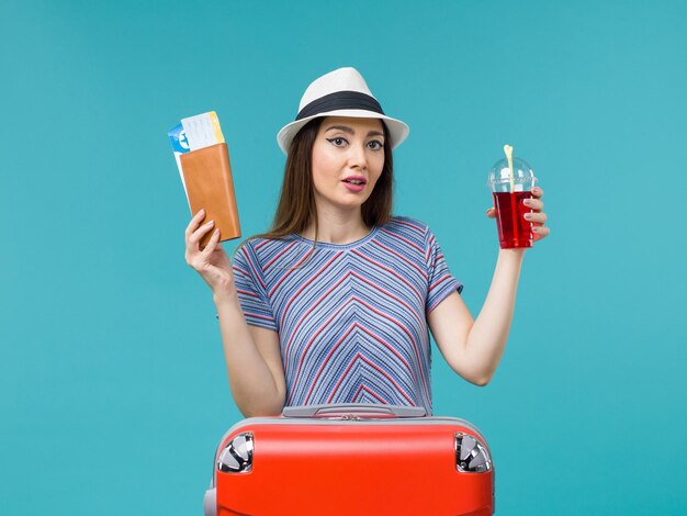 Mujer de vista frontal en vacaciones sosteniendo boletos y jugo rojo sobre el fondo azul viaje de viaje por mar vacaciones femeninas