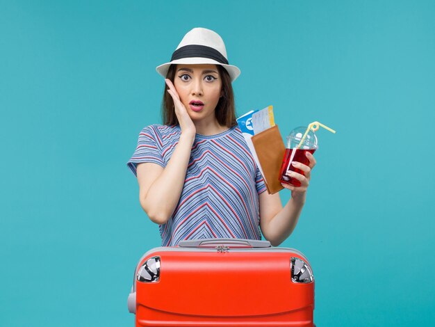 Mujer de vista frontal en vacaciones sosteniendo jugo con boletos sobre fondo azul viaje de avión de viaje de verano de mar femenino