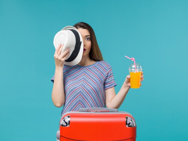 Mujer de vista frontal en vacaciones sosteniendo jugo en el fondo azul viaje viaje vacaciones mar viaje