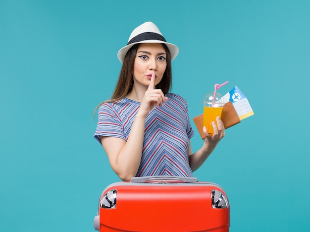Mujer de vista frontal en vacaciones con su bolsa roja sosteniendo boletos y jugo sobre fondo azul claro viaje viaje viaje vacaciones hembra