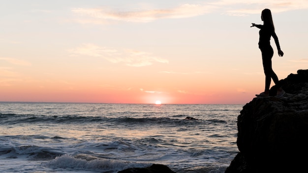 Mujer de vista lateral apuntando a la puesta de sol con espacio de copia