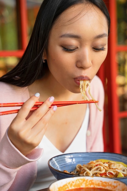 Mujer de vista lateral comiendo fideos sabrosos