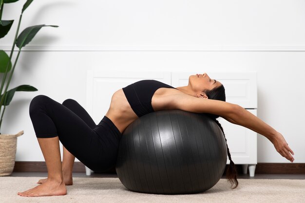 Mujer de vista lateral fortaleciendo el piso pélvico con pelota