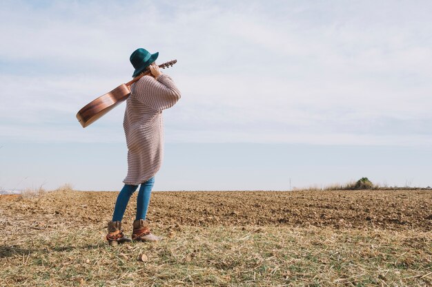 Mujer de vista lateral con guitarra en el campo