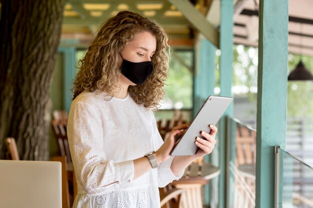 Mujer de vista lateral con máscara con tableta