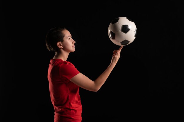 Mujer de vista lateral con pelota de fútbol