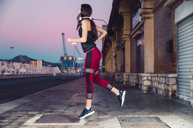 Foto gratuita mujer de vista lateral que se ejecuta en el pavimento