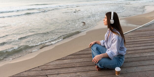 Mujer de vista lateral sentada junto a la playa con espacio de copia