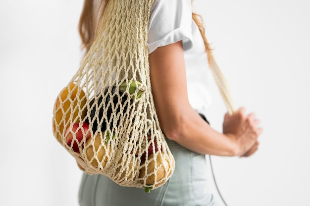 Mujer de vista lateral sosteniendo una bolsa reciclable