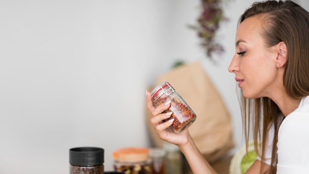 Mujer de vista lateral sosteniendo un frasco con especias