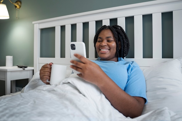 Foto gratuita mujer de vista lateral con teléfono inteligente en la cama