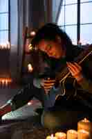 Foto gratuita mujer de vista lateral tocando la guitarra en casa