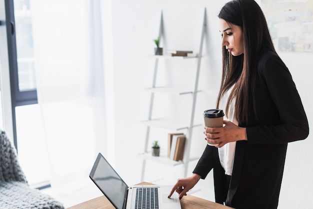 Foto gratuita mujer de vista lateral usando la computadora portátil en la oficina