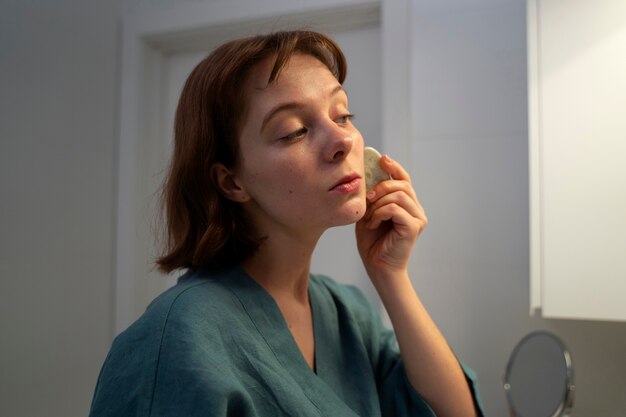 Mujer de vista lateral usando gua sha para masaje