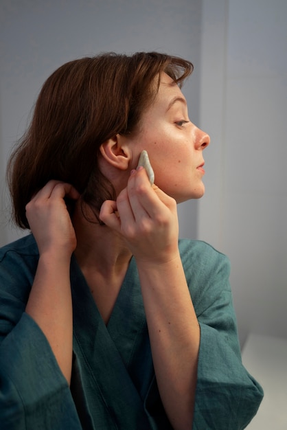 Foto gratuita mujer de vista lateral usando gua sha para masaje