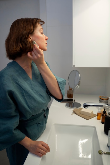 Foto gratuita mujer de vista lateral usando gua sha para masaje