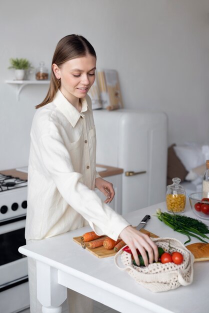 Mujer de vista lateral con verduras en la cocina