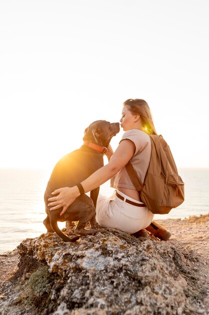 Mujer de vista posterior abrazando a su perro al atardecer