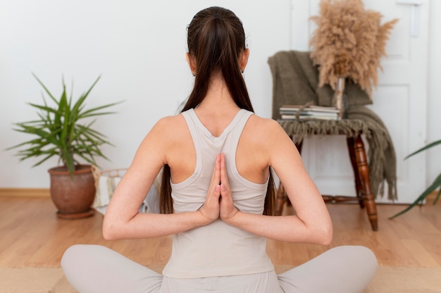 Mujer de vista posterior meditando en casa