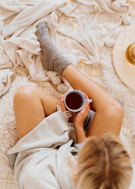 Mujer de vista superior sosteniendo una taza de té mientras disfruta de las vacaciones de invierno