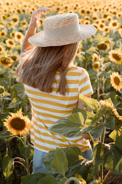 Mujer de vista trasera en campo de girasol